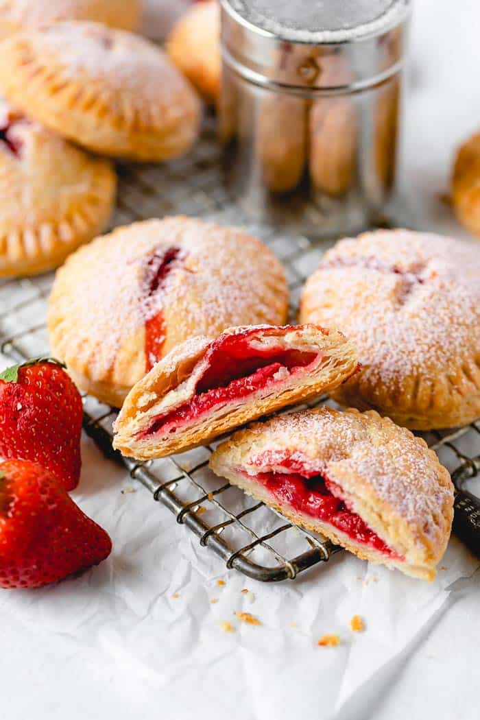 Strawberry hand pies on a wire rack with one cut open ready to enjoy
