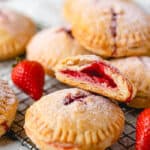 A close up of strawberry hand pies with one cut open showing strawberry filling