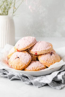 Strawberry powdered sugar falling down on a stack of hand pies