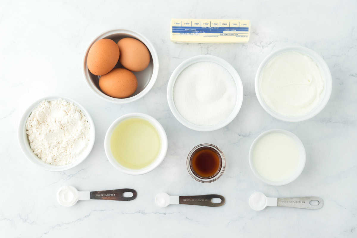 eggs, butter, flour, leavening, salt, vanilla, sugar in white bowls on a white background