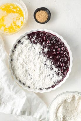 Blueberry filling in a white casserole dish with cake mix on top