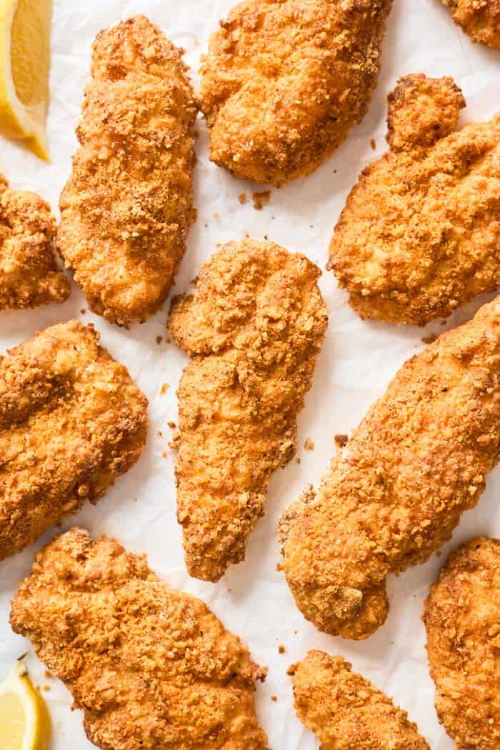 Air Fryer Fried Chicken tenders against white background with lemon slices