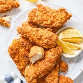 Air fryer fried chicken pieces on a white tray with lemon wedges ready to serve