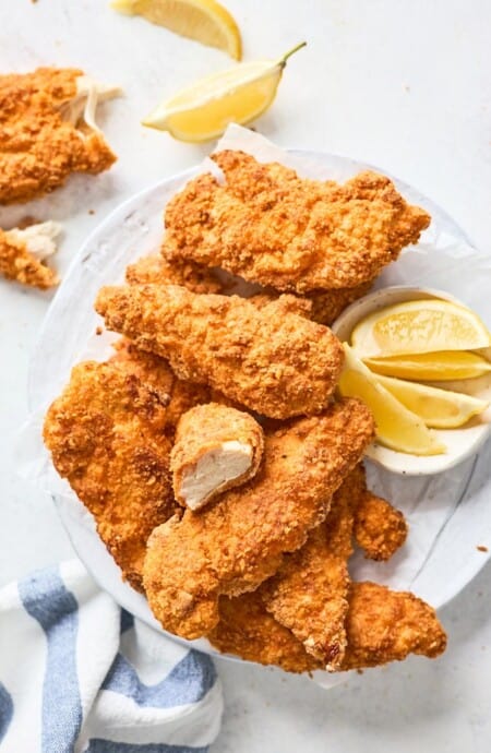 Air fryer fried chicken pieces on a white tray with lemon wedges ready to serve
