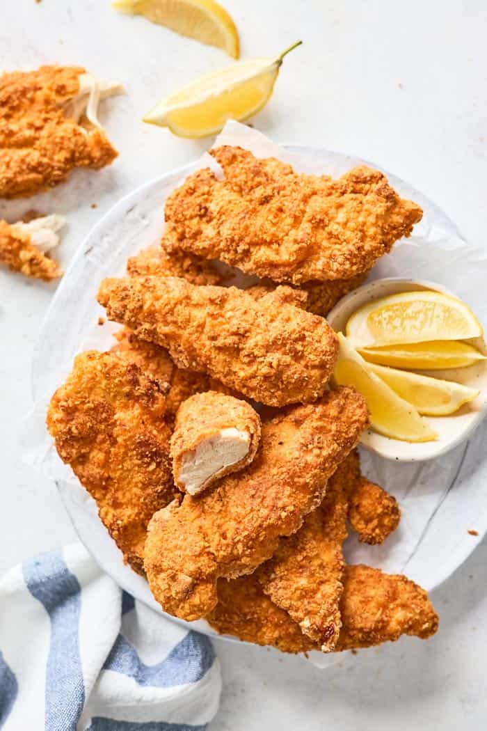 Air fryer fried chicken pieces on a white tray with lemon wedges ready to serve