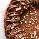 A close up of frosting cake with chocolate frosting and sprinkles