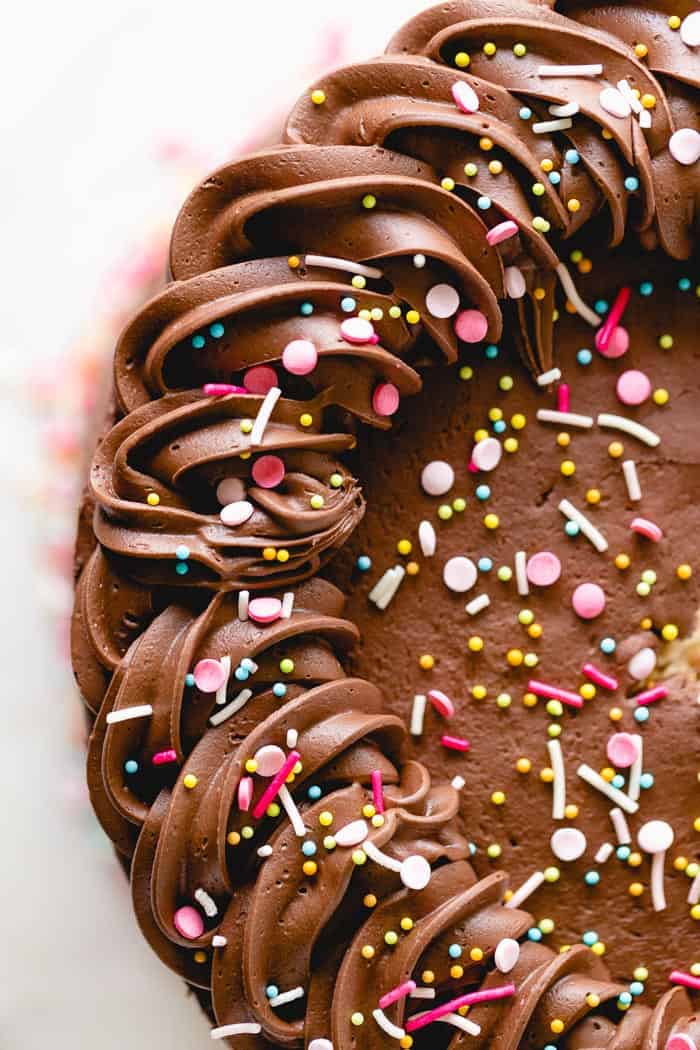 A close up of frosting cake with chocolate frosting and sprinkles