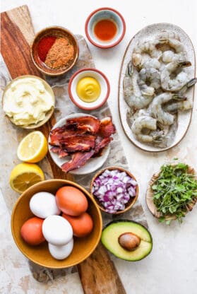 Ingredients like raw shrimp, bacon, eggs, avocado in separate bowls