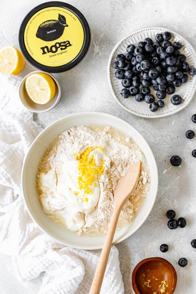 Lemon biscuit batter being mixed together with blueberries in a bowl