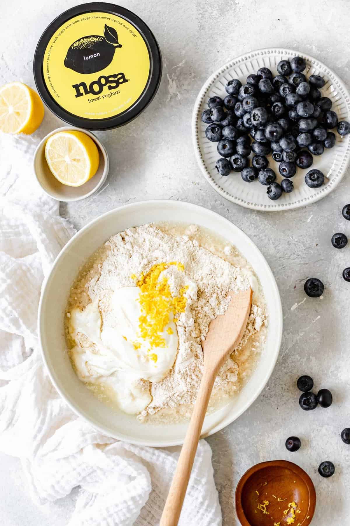 Lemon biscuit batter being mixed together with blueberries in a bowl