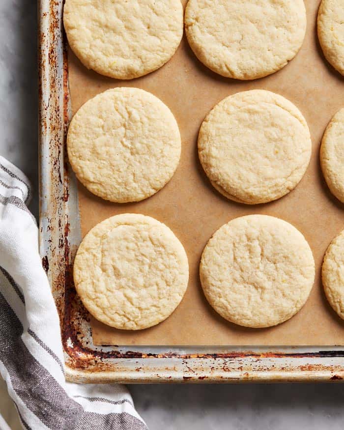 Tea cake cookies lined on a parchment baking sheet after baking