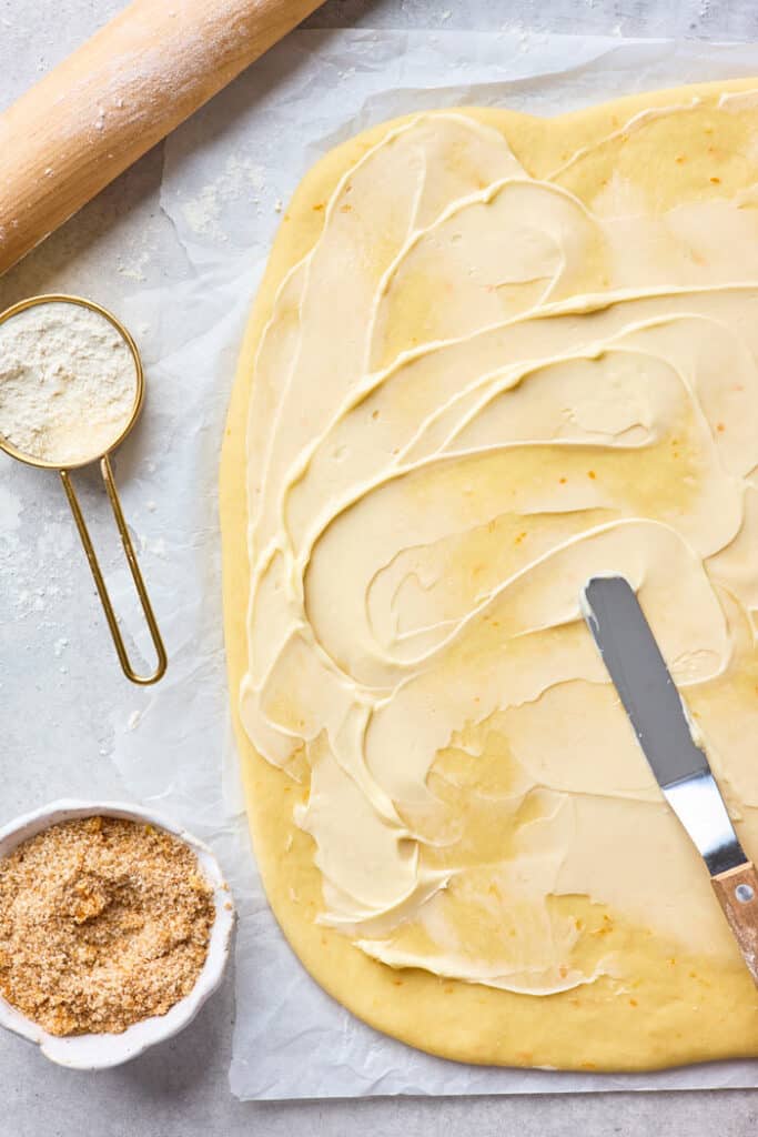 Pastry roll dough rolled out with butter being slathered over the top