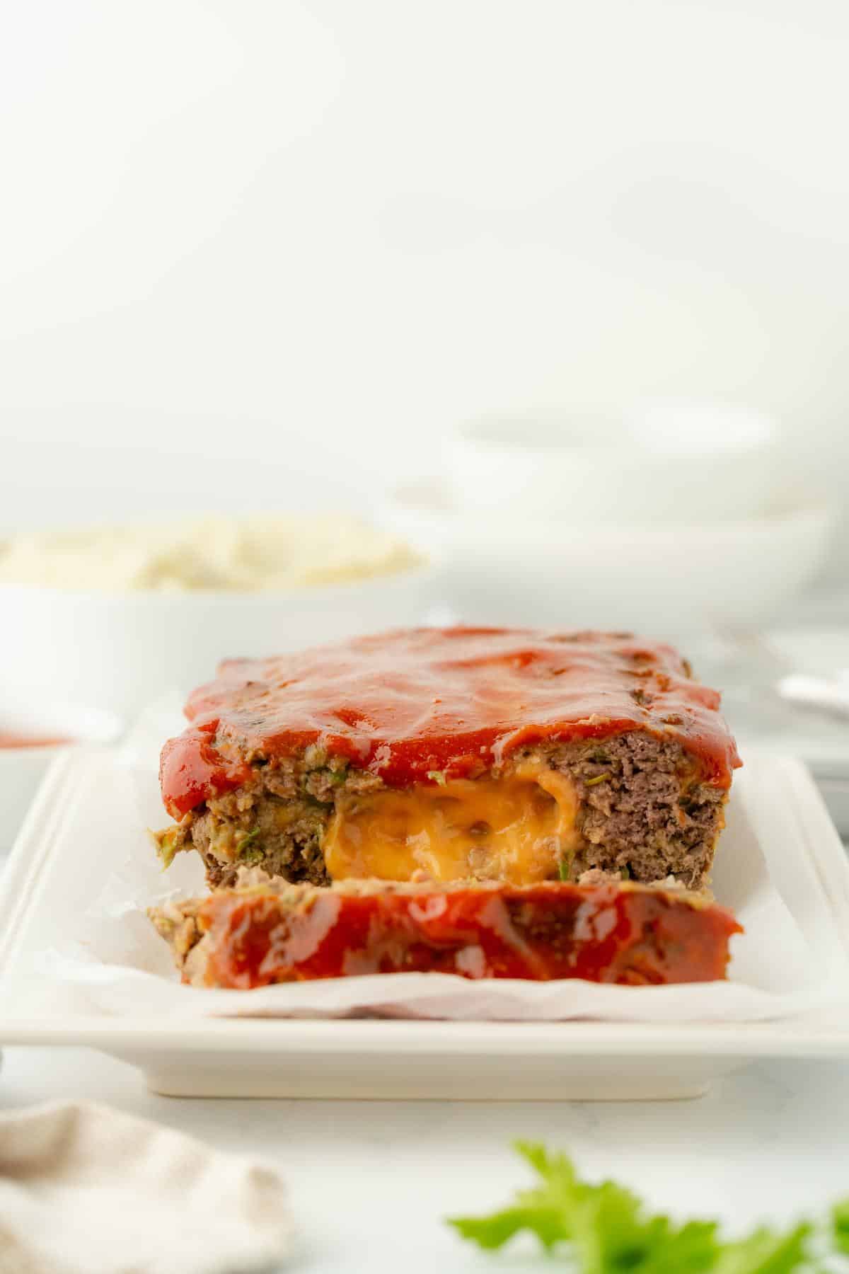 Sliced stuffed meatloaf with a visible gooey cheese center and glazed top