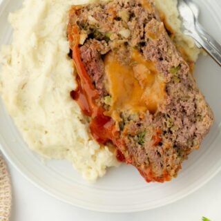 Overhead view of stuffed meatloaf served with mashed potatoes on a plate