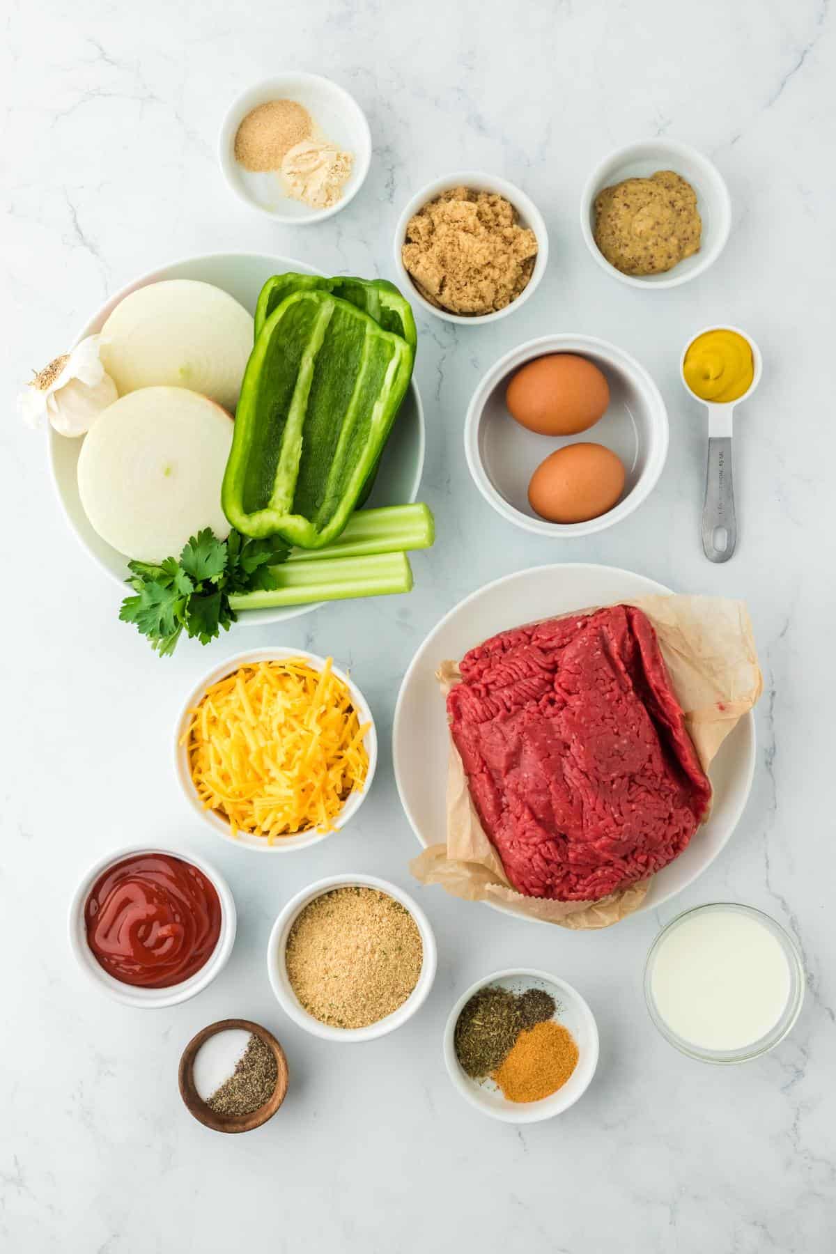 Overhead shot of ingredients to make stuffed meatloaf on a marble surface beefore cooking