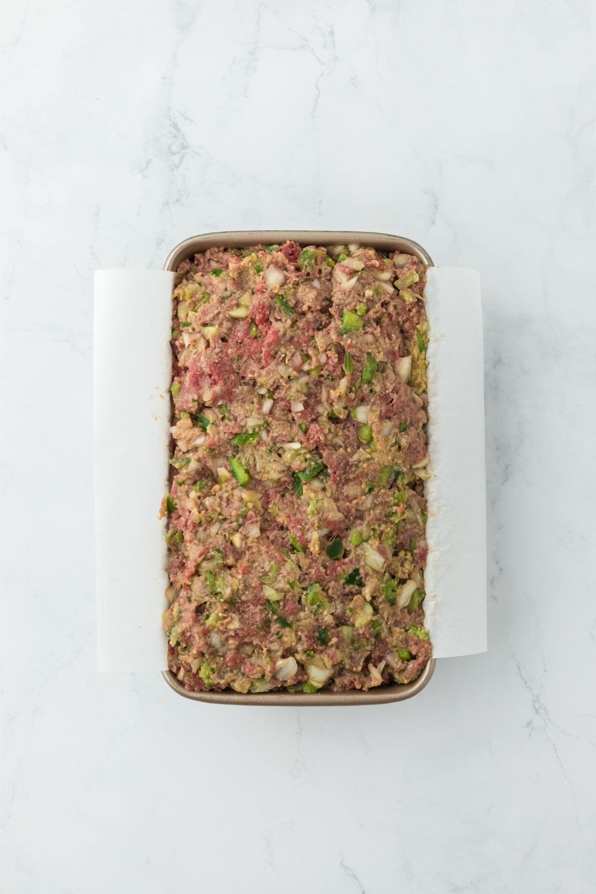 Meatloaf mixture completely assembled in a parchment-lined loaf pan