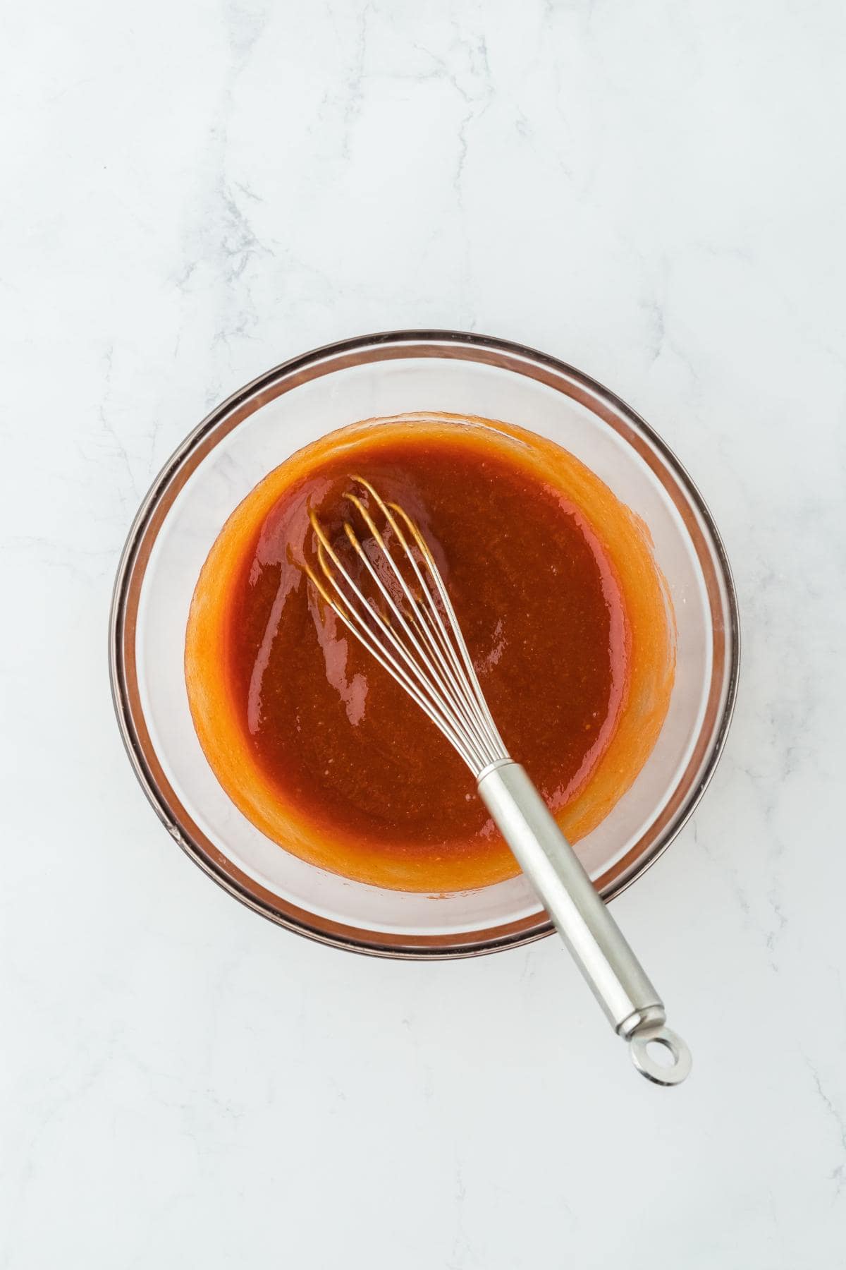 A glass bowl with fully whisked meatloaf glaze