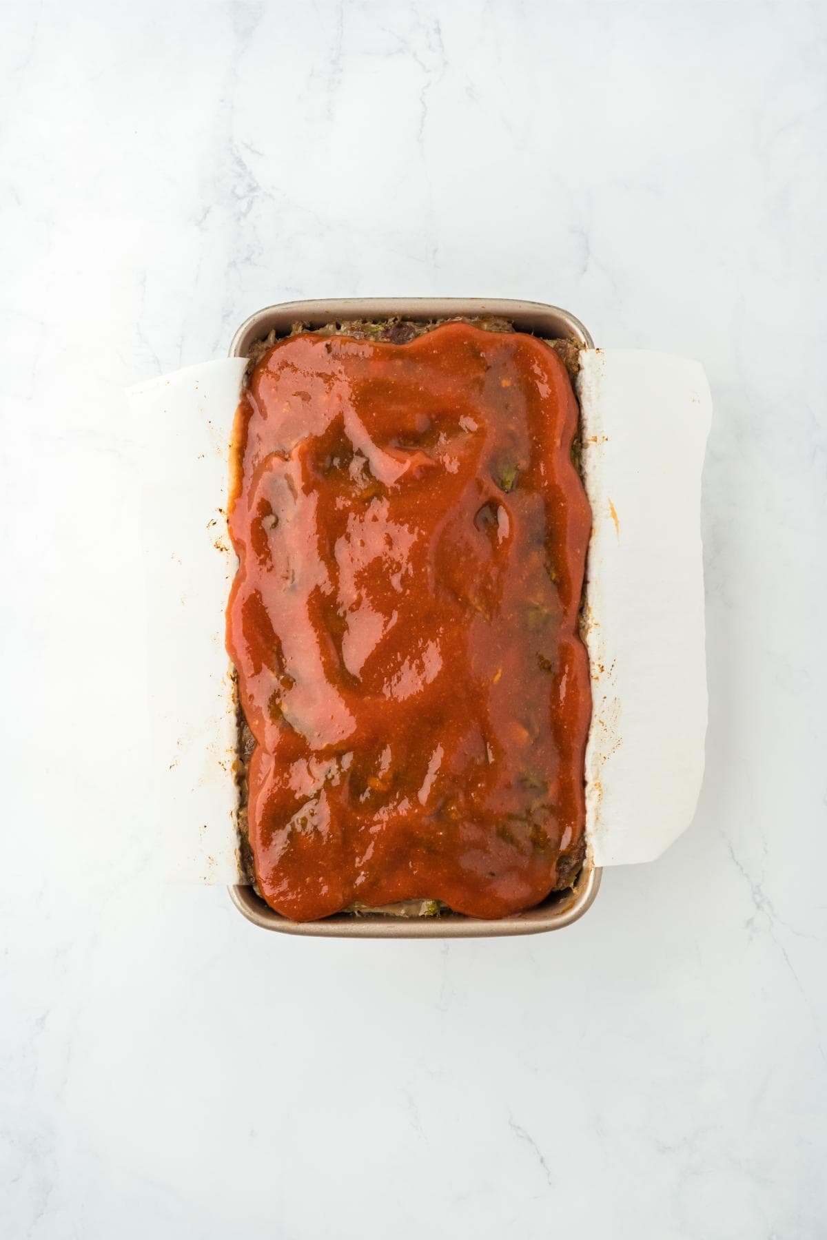 Meatloaf in a loaf pan fully coated with a layer of glaze