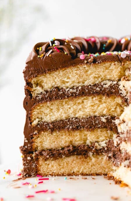 A close up of a sliced yellow birthday cake with sprinkles on top