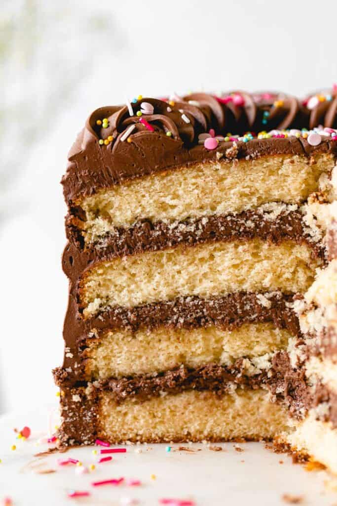 A close up of a sliced yellow cake with sprinkles on top