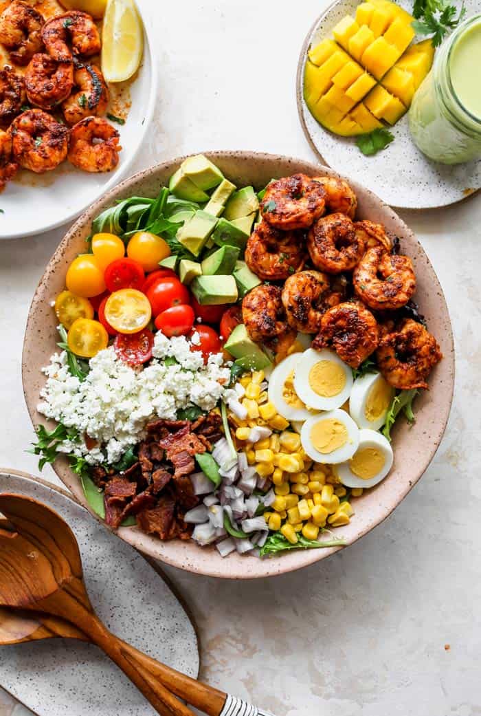 Ingredients for a cobb salad separated in a large pink bowl