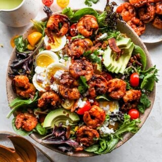 A delicious cobb salad with jerk shrimp and dressing in a pink bowl ready to enjoy