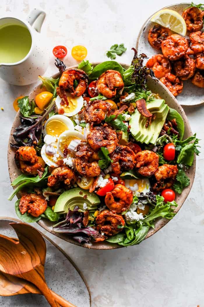 A delicious cobb salad with jerk shrimp and dressing in a pink bowl ready to enjoy