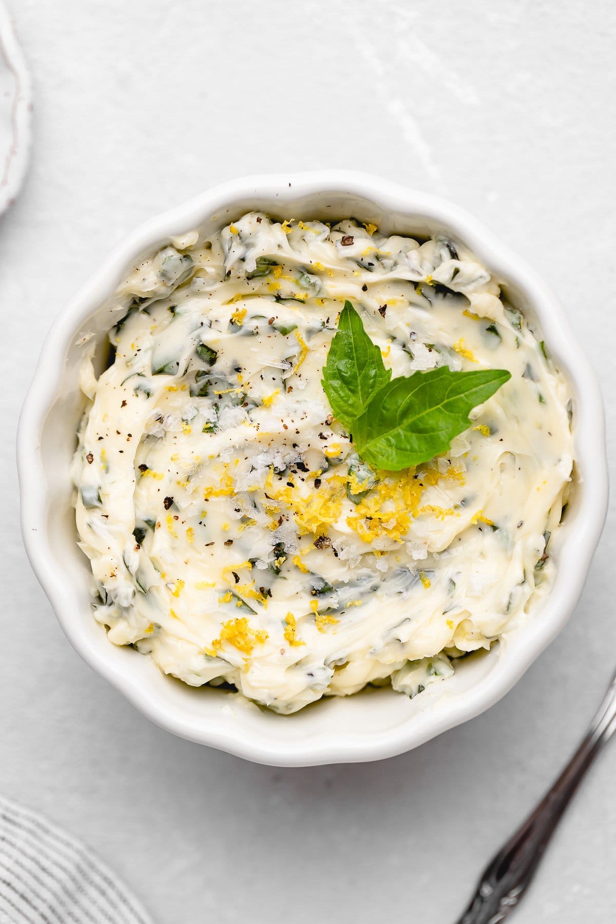 A white bowl of basil butter, topped with a basil leaf