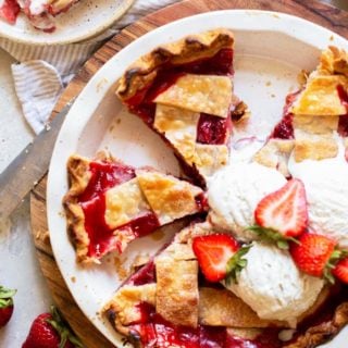 An overhead image of slices of pie with a lattice crust and strawberries and vanilla ice cream