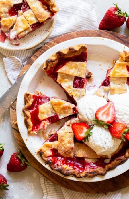 An overhead image of slices of pie with a lattice crust and strawberries and vanilla ice cream