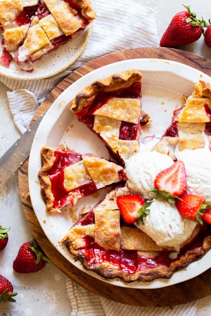 An overhead image of slices of pie with a lattice crust and strawberries and vanilla ice cream