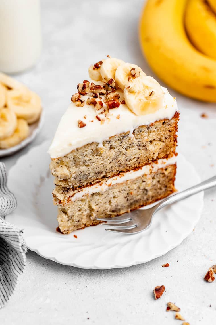 A slice of banana cake standing up on a white plate ready to enjoy