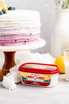 A close up of ombre blueberry cake with a butter carton in white background