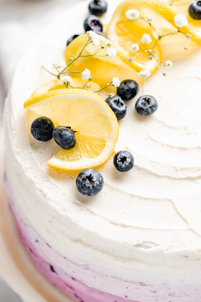 A close up of cream cheese frosting on cake with lemon slices and blueberries