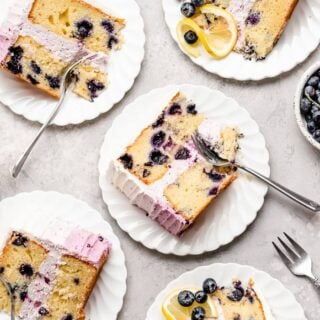 Blueberry lemon layer cake slices on white plates ready to serve with silver forks
