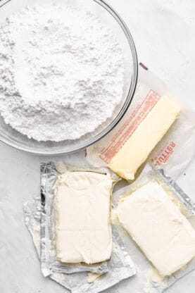 Butter, cream cheese and confectioner's sugar against a white background before mixing into frosting