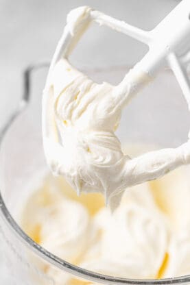 A close up of mixer beater with fluffy frosting on it