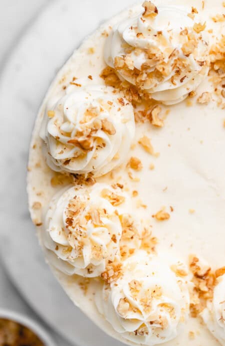 An overhead photo of a cream cheese buttercream frosted cake with nuts on top