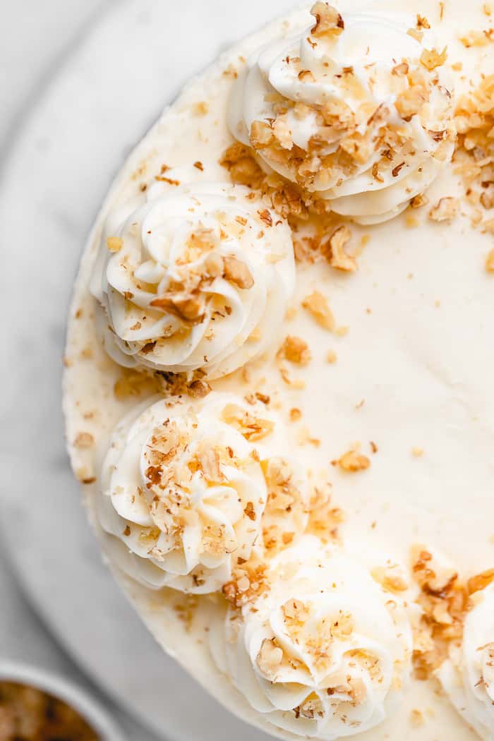 An overhead photo of a cream cheese buttercream frosted cake with nuts on top