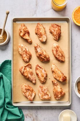 Seasoned chicken wings on a parchment lined baking sheet ready to bake