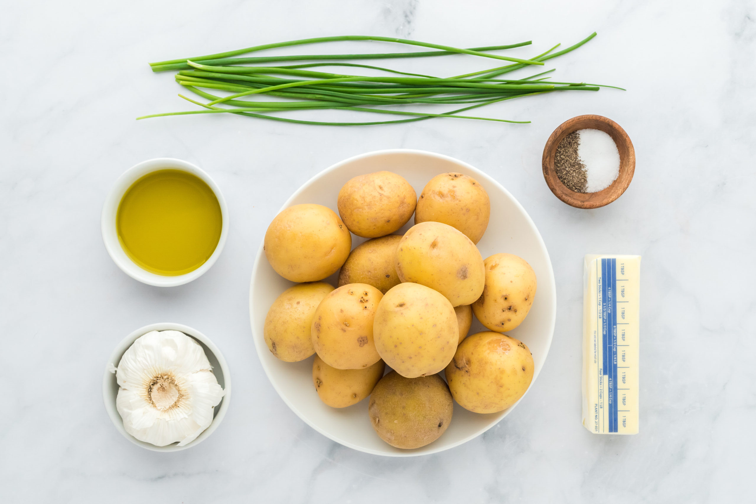 Yukon gold potatoes, butter, garlic, buttery and thyme on white countertop