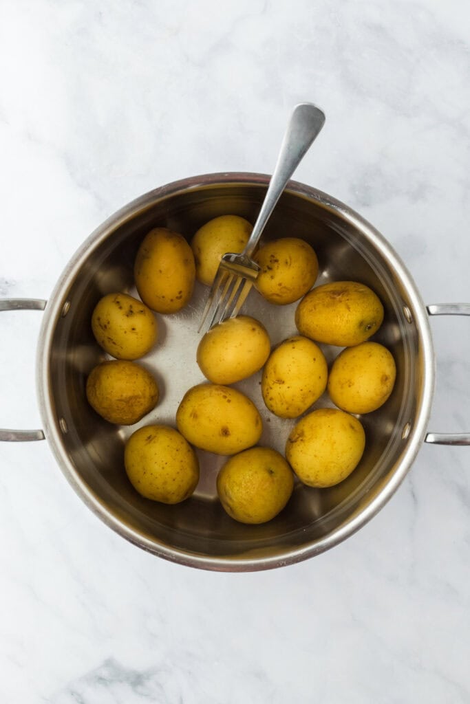 Boiled yukon gold potatoes in a pot with a fork checking to see if they were tender