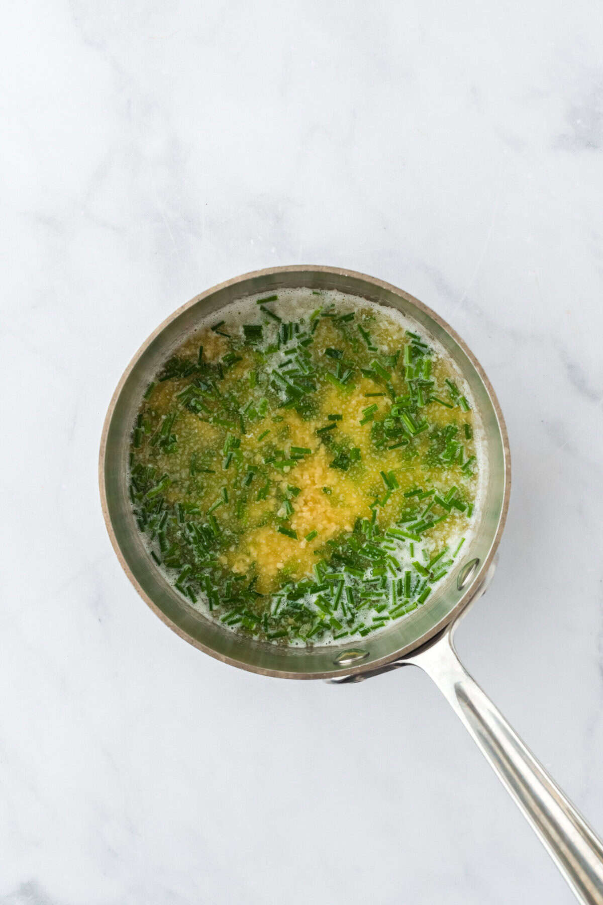 Combined garlic chive butter to make smash potatoes recipe on white countertop