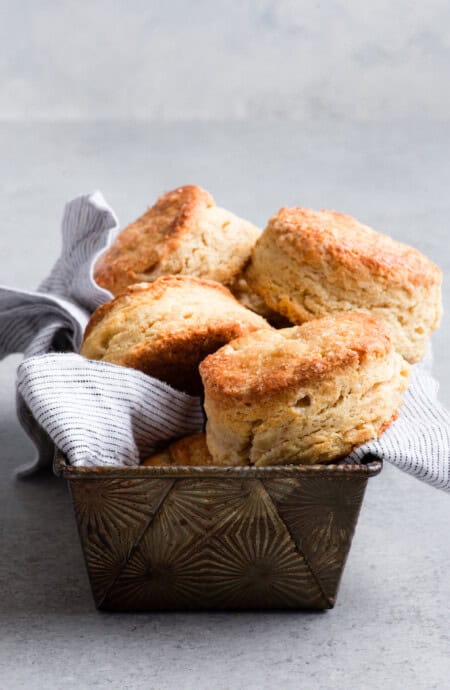 Sour cream biscuits piled high on a napkin lined tin ready to serve