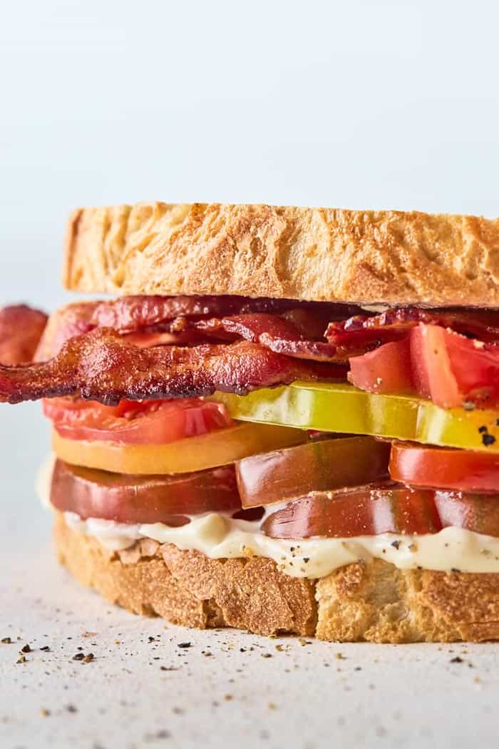 A close up of a tomato sandwich with heirloom tomatoes and bacon slices ready to enjoy.