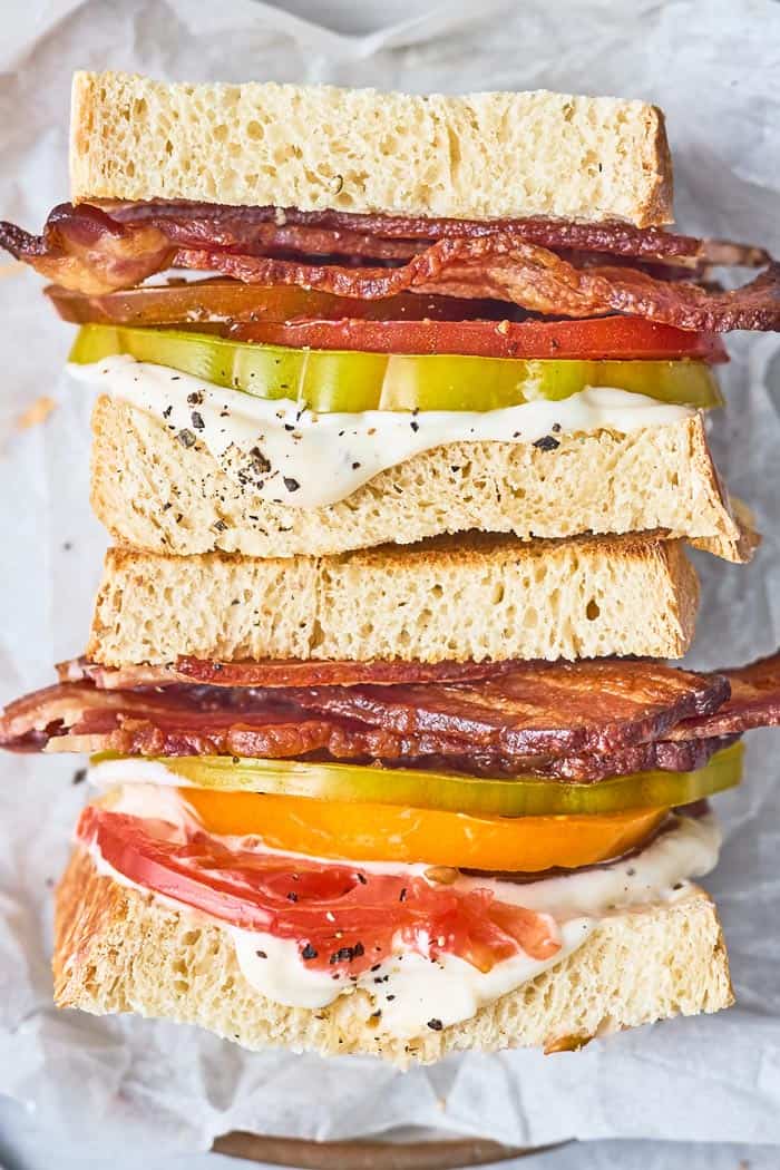 Two bacon and tomato sandwiches stacked on top of each other ready to eat
