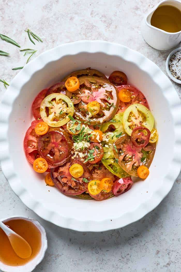 Fresh summer tomato slices in a white bowl against a white background