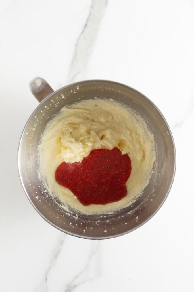 Strawberry puree being added to a cupcake batter in mixing bowl
