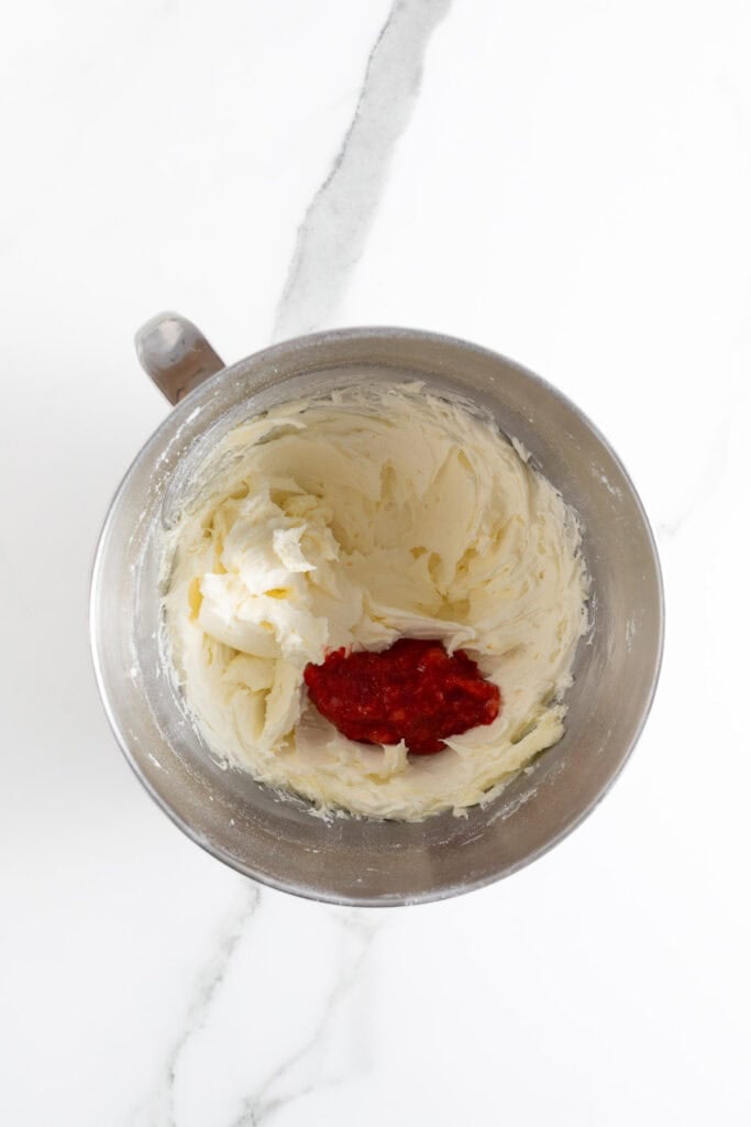 Creamed butter and sugar in a mixing bowl with strawberry puree added