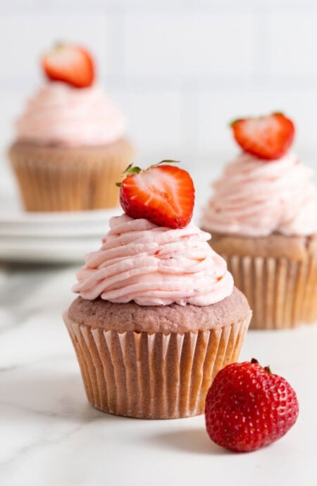 A close up of strawberry cupcakes on white plates